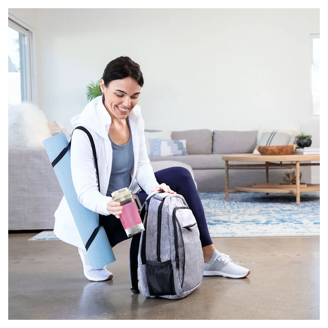 Woman putting a Ninja Blast Max portable blender into a backpack
