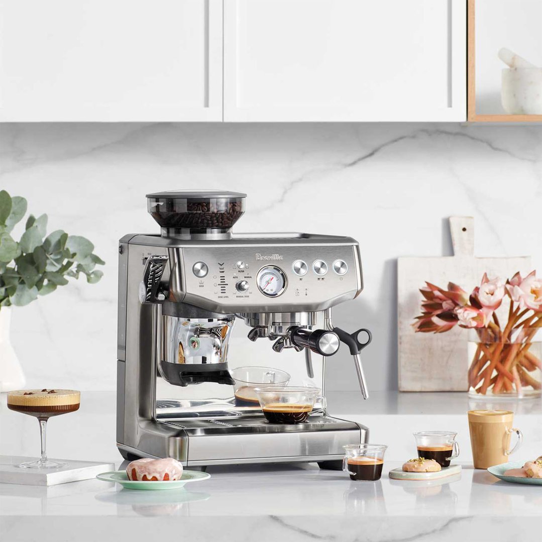 Breville coffee machine on a kitchen counter with coffee drinks and pastries