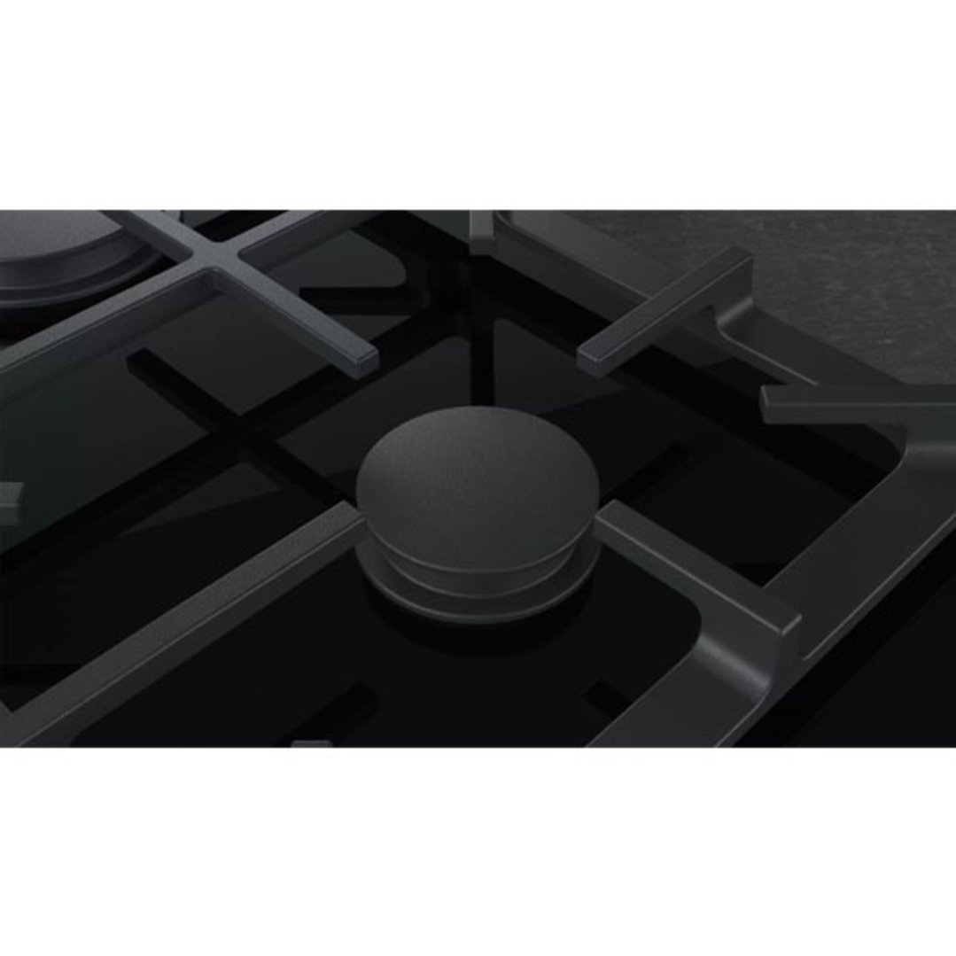 Close up of a black gas cooktop with dark grates and control knob