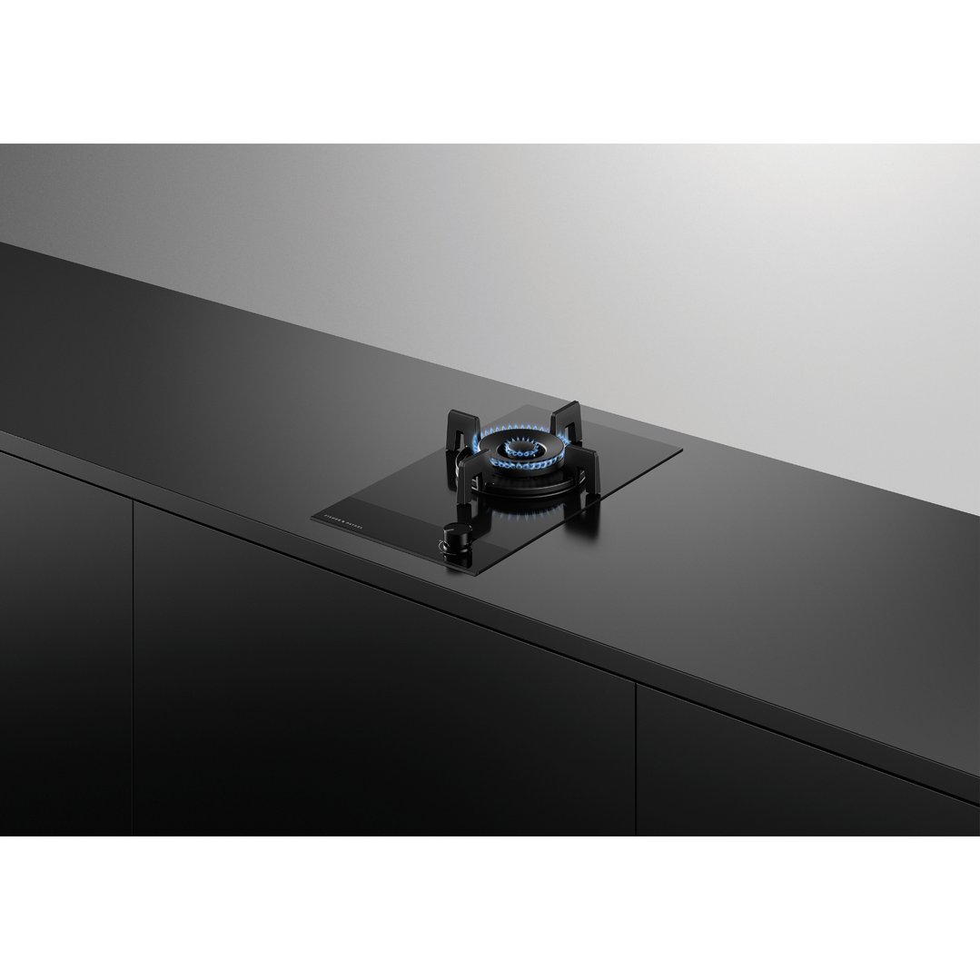A black gas on glass cooktop with blue flames on a black countertop