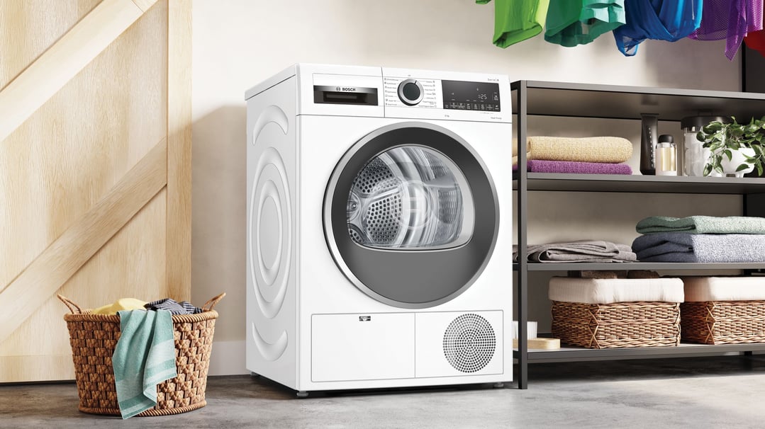 White Bosch heat pump dryer in a laundry room with a laundry basket
