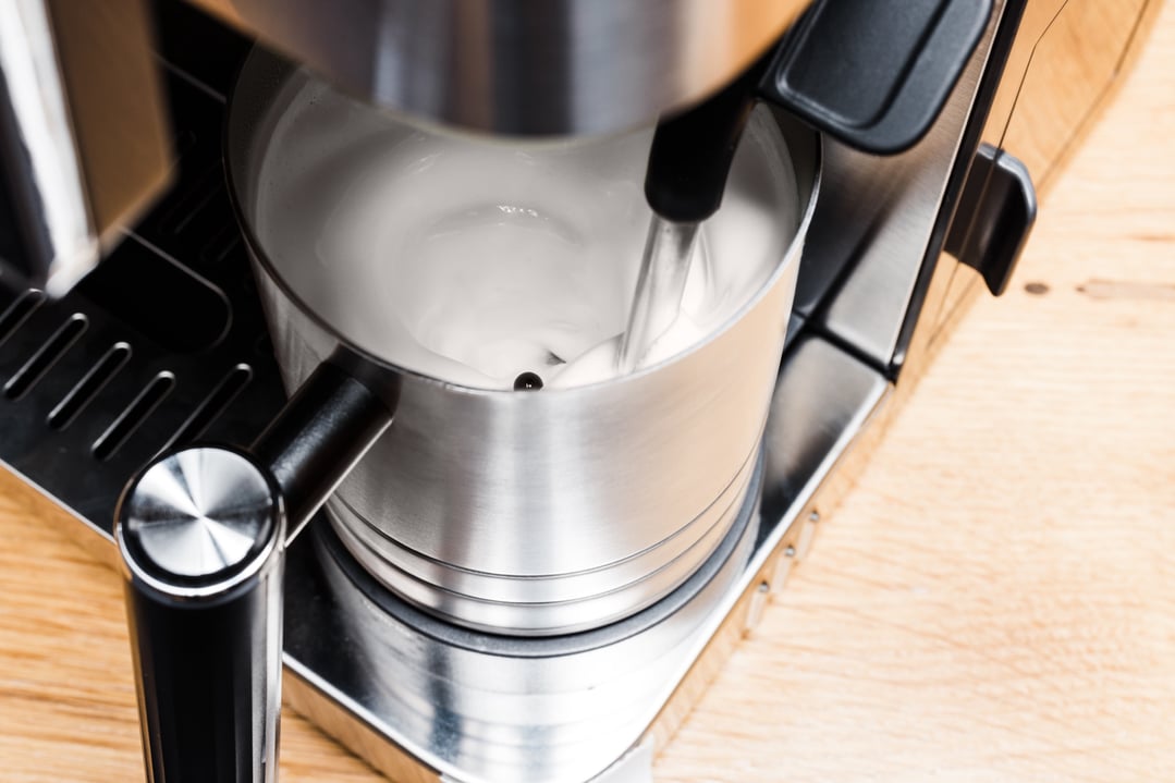 Close up of milk frothing in the espresso machine's stainless steel pitcher