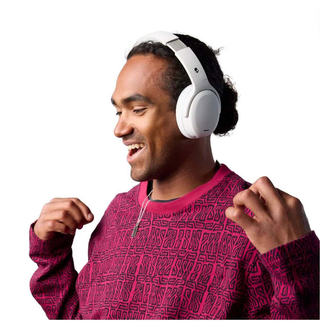 Man wearing white Skullcandy Crusher ANC 2 headphones, smiling and gesturing