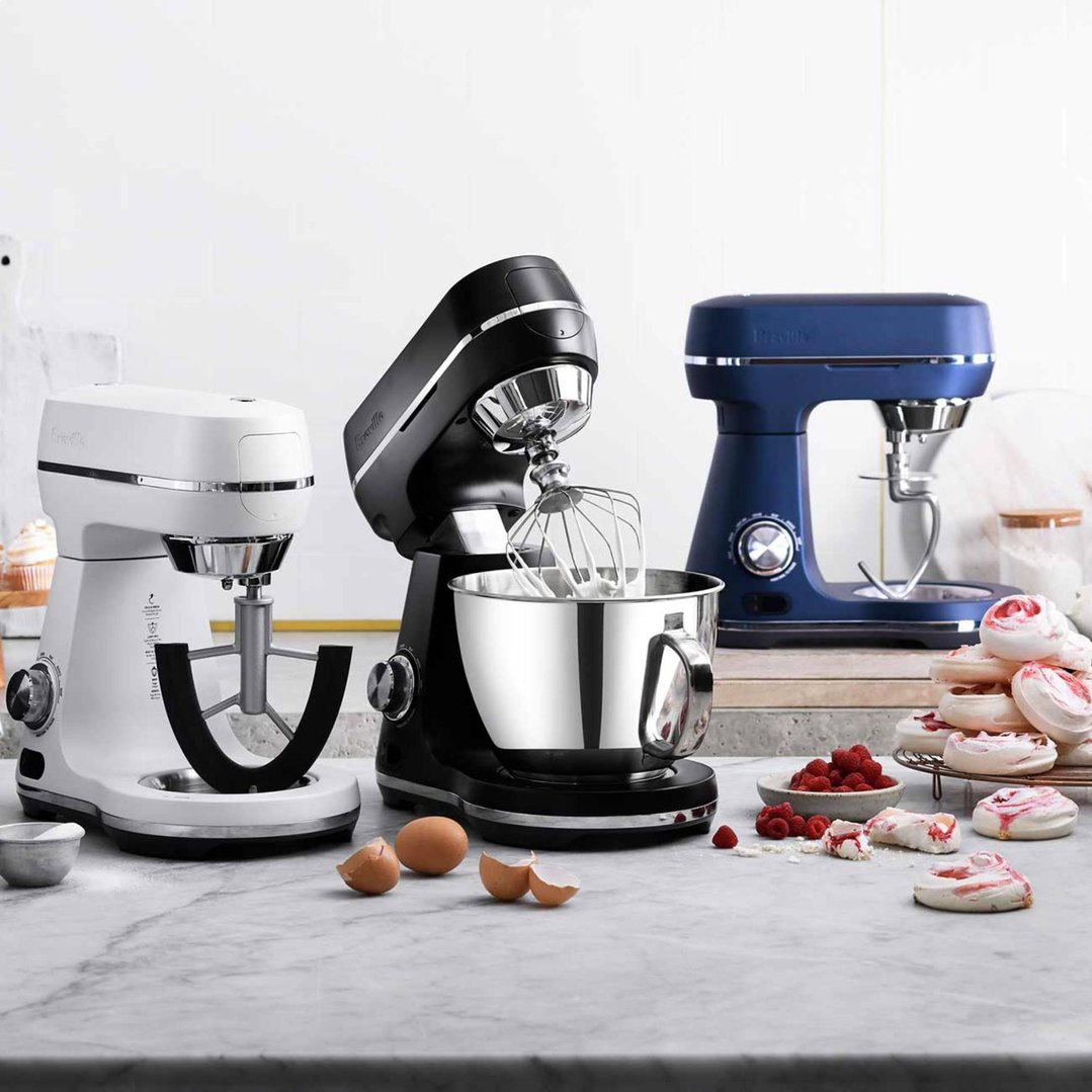 Three Breville food mixers in white, black, and blue on a marble counter