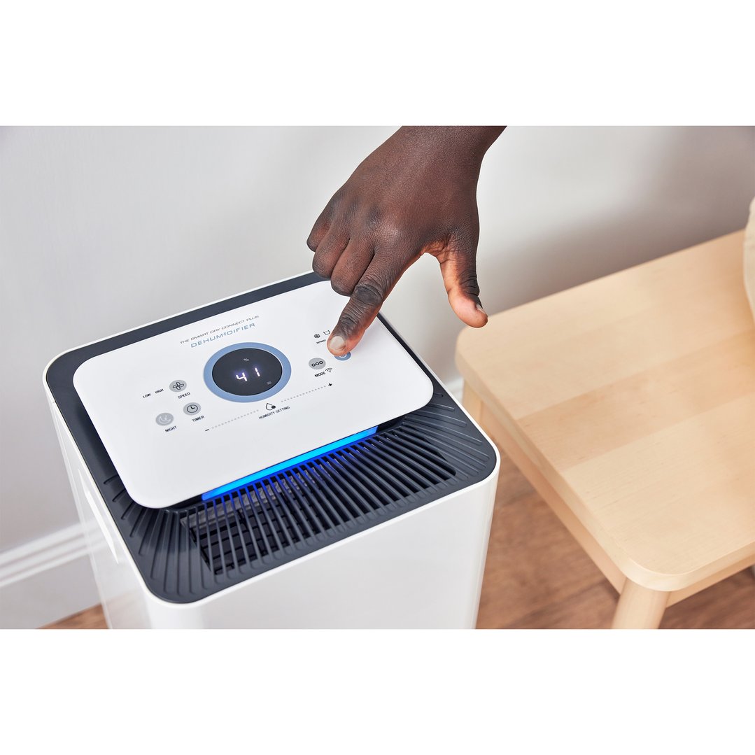 Person's hand pressing a button on the Breville Smart Dry Connect Dehumidifier