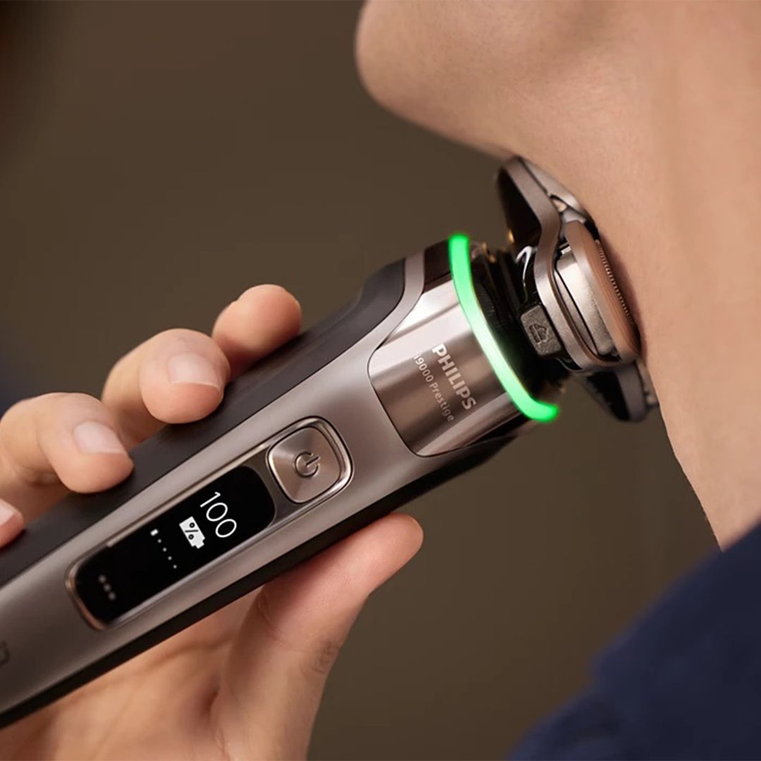 Hand holding a Philips electric shaver to a person's neck