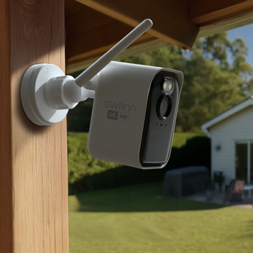 Swann security camera mounted on a wooden post overlooking a backyard