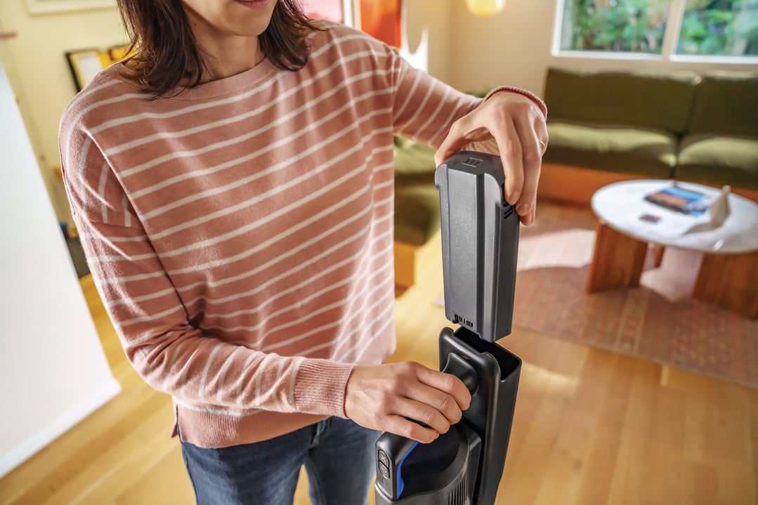 Woman inserting the battery into a BISSELL handStickVacuum in a living room