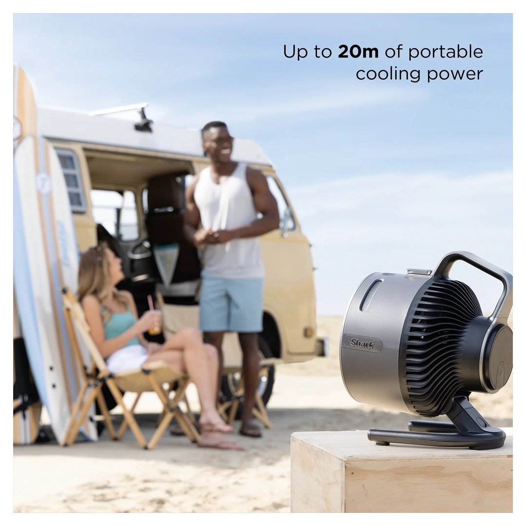 Shark portable fan on a wooden crate on a beach with people and a van