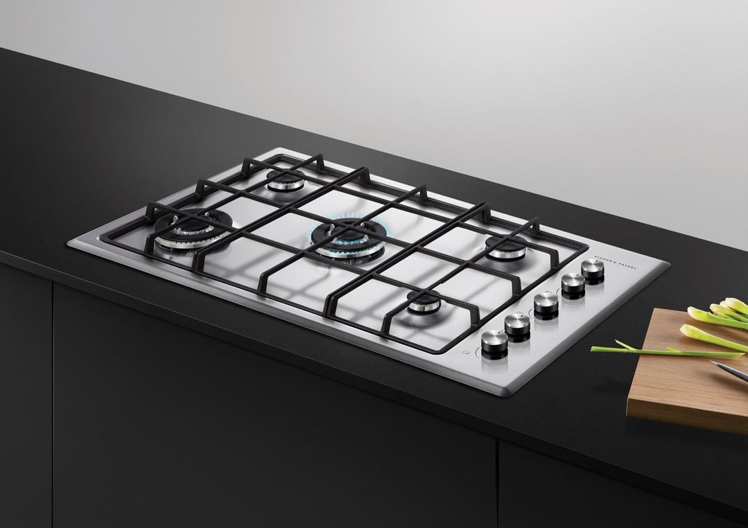 Stainless steel gas cooktop with five burners on a black countertop