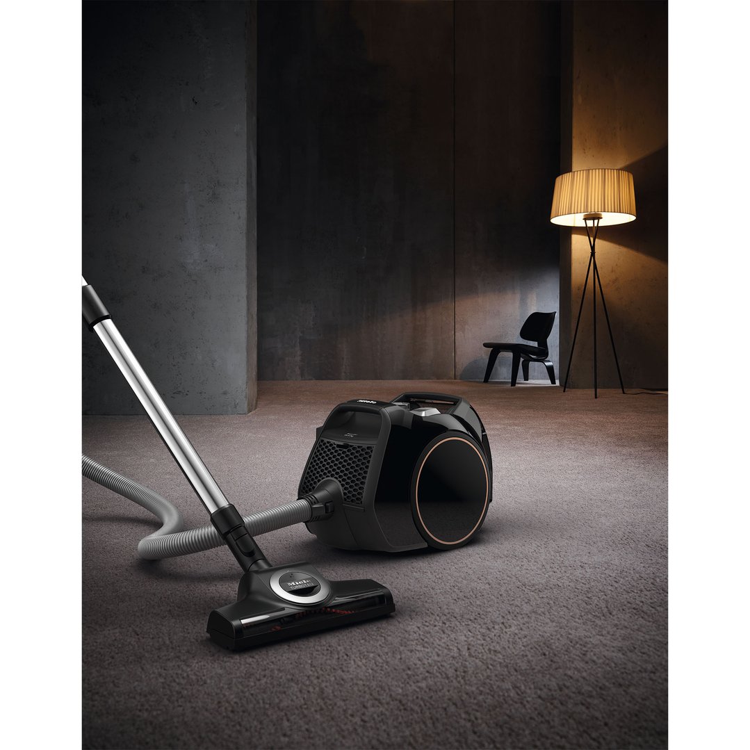 Miele Boost CX1 vacuum cleaner on carpet in a dimly lit room