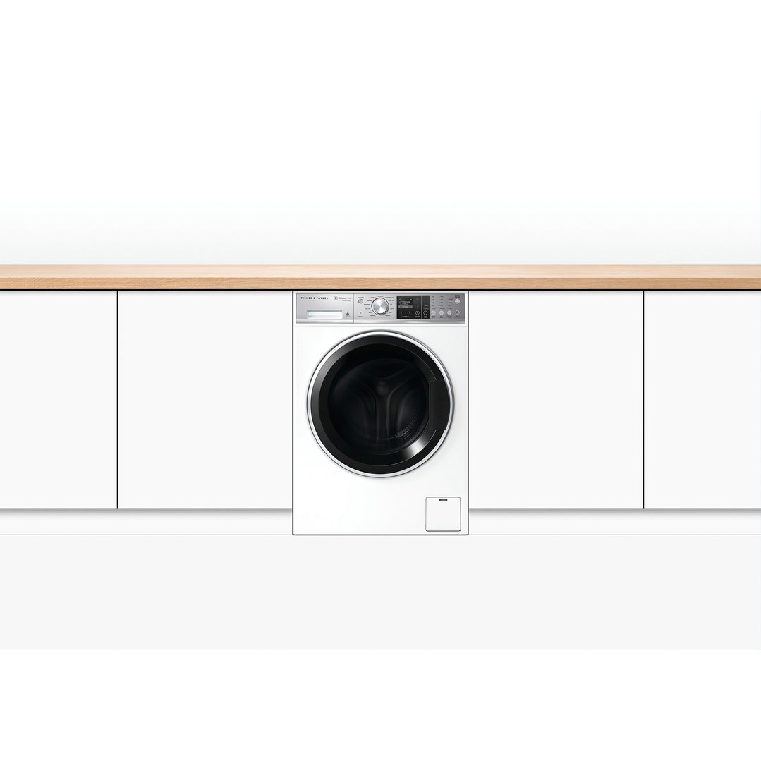 A white Fisher & Paykel washing machine built into white cabinetry under a wooden countertop