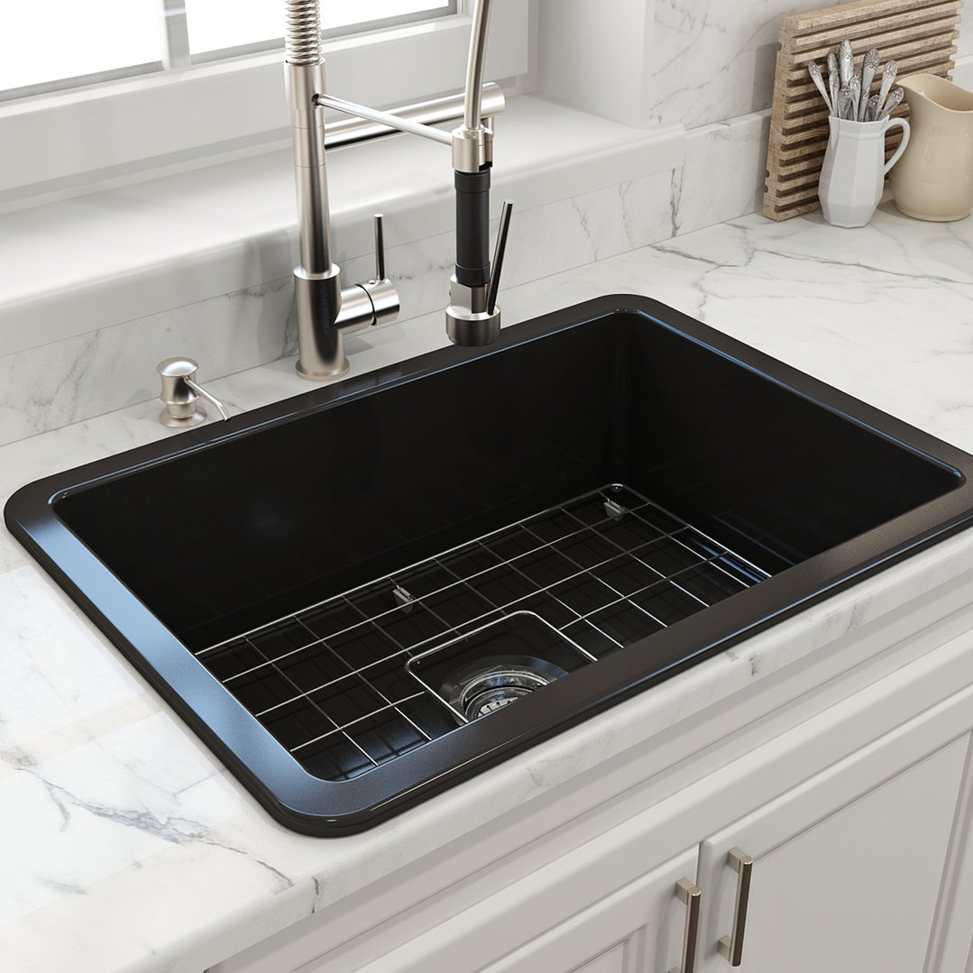 Matte black sink with a metal grid in a white marble kitchen