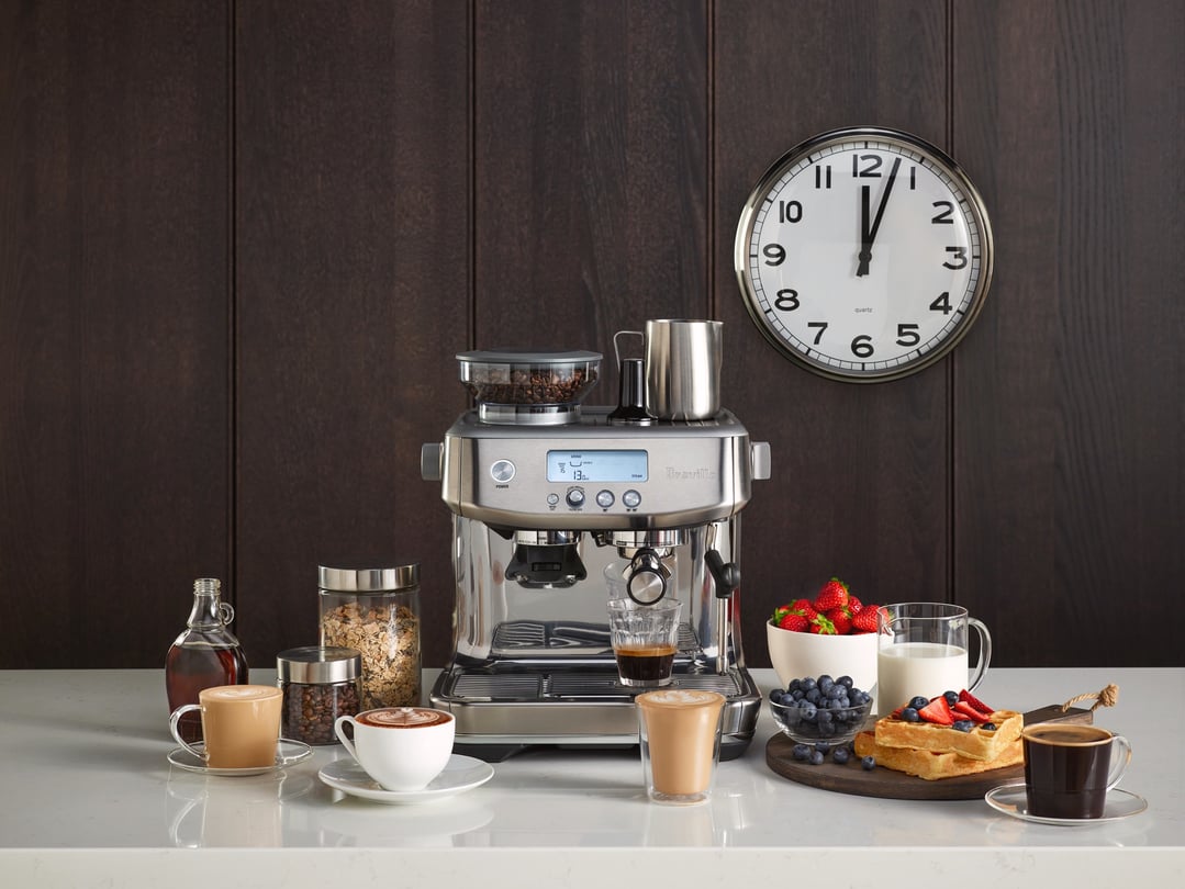 Breville Barista Pro coffee machine on a counter with coffee, waffles, and fruit