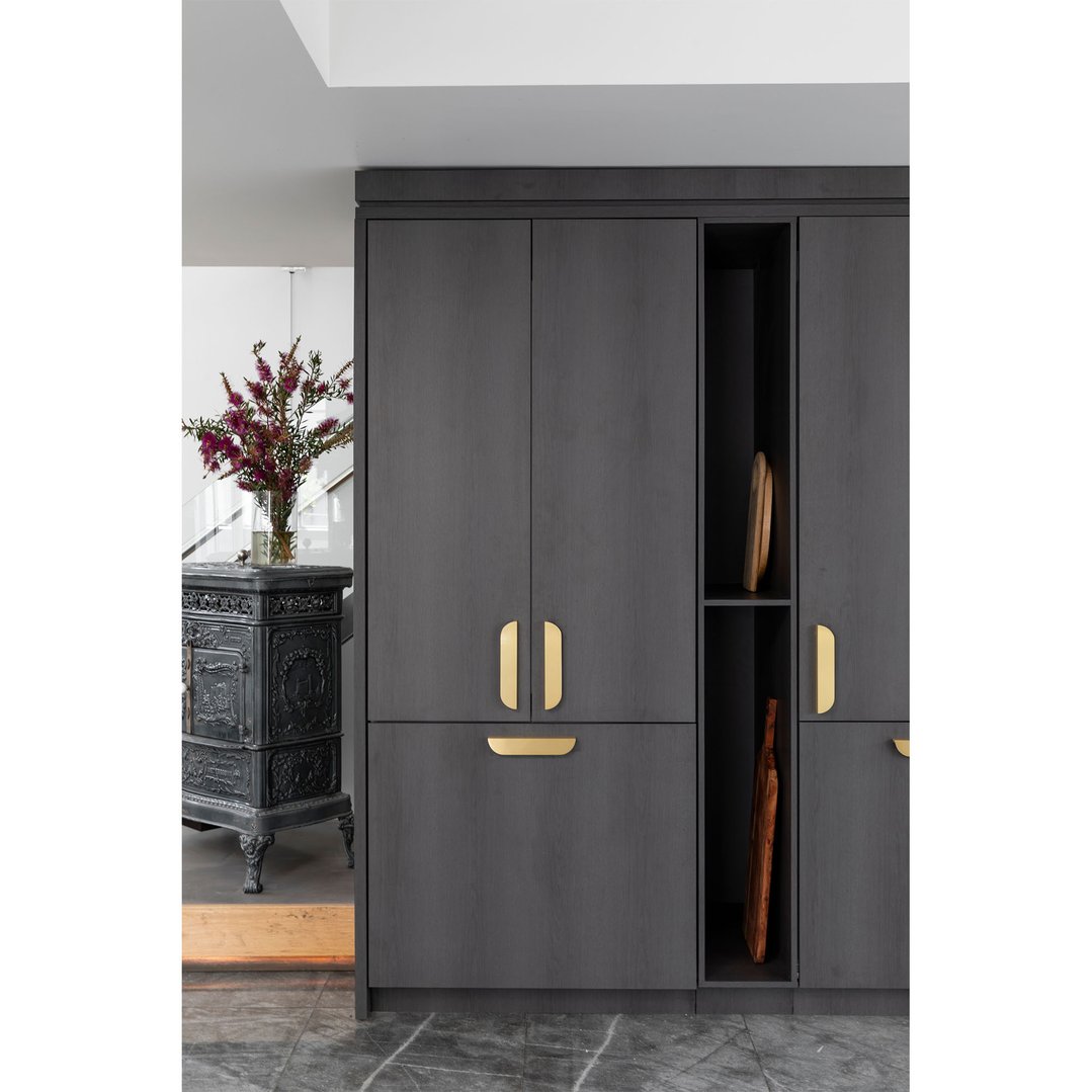 Dark grey integrated fridge with gold handles in a modern kitchen setting