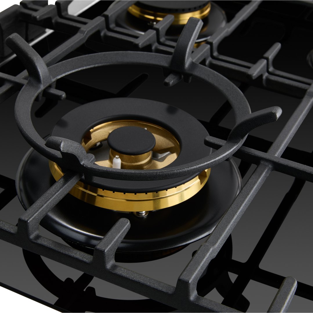 Close up of a black gas on glass cooktop with brass burners