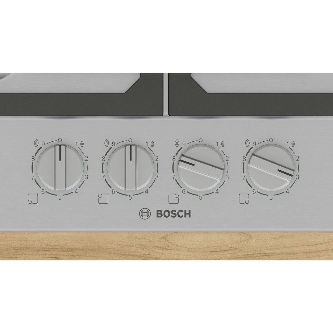 Close up of a Bosch cooktop with four control knobs on a wooden surface