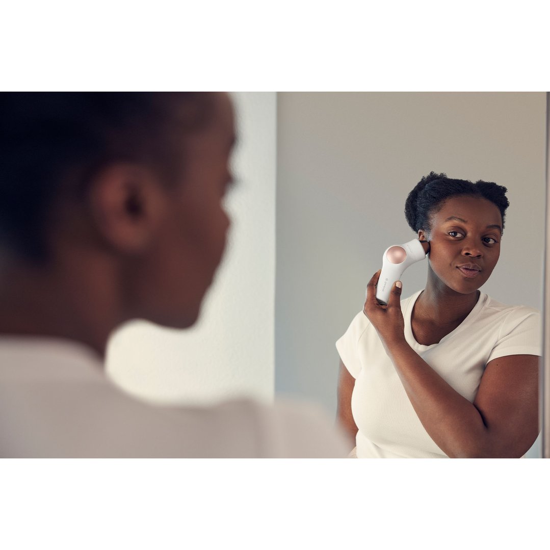 Woman using a TheraFace PRO device on her face, looking into a mirror