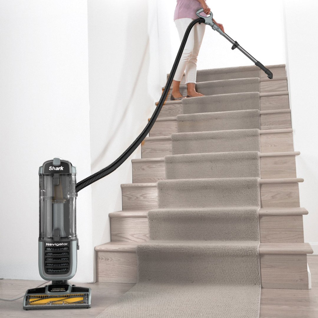 Woman vacuuming carpeted stairs with a Shark Navigator Pet Vacuum