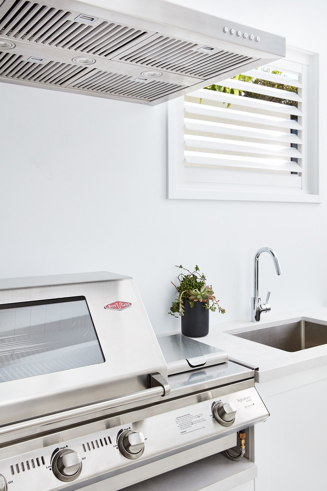Stainless steel rangehood above a barbecue grill in an outdoor kitchen setting