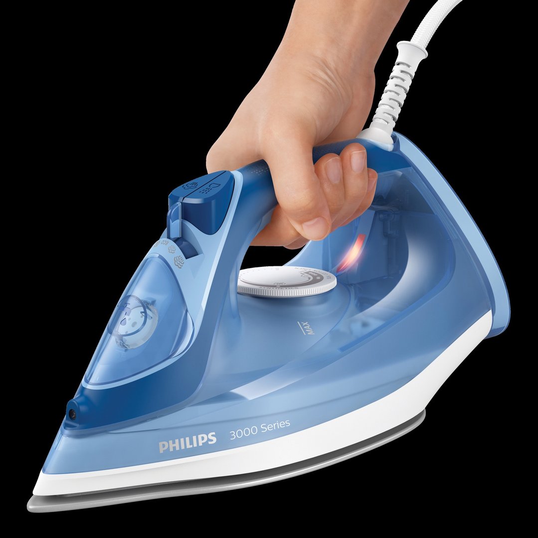 Hand holding a blue Philips 3000 Series steam iron on a black background