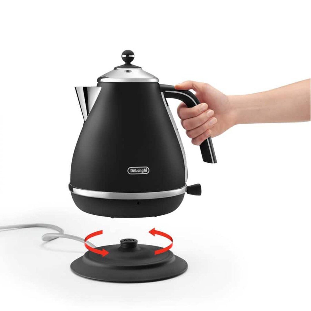 Hand placing a black DeLonghi kettle onto its rotating power base