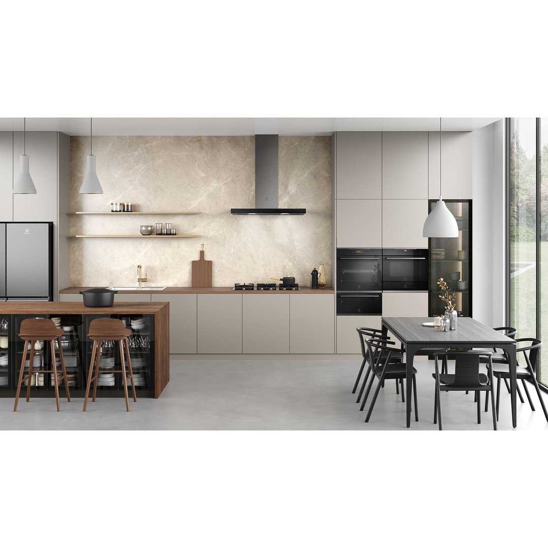 Two ovens built into light cabinetry in a modern kitchen with dining area