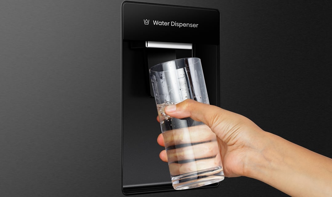Hand holding a glass of water under the fridge water dispenser
