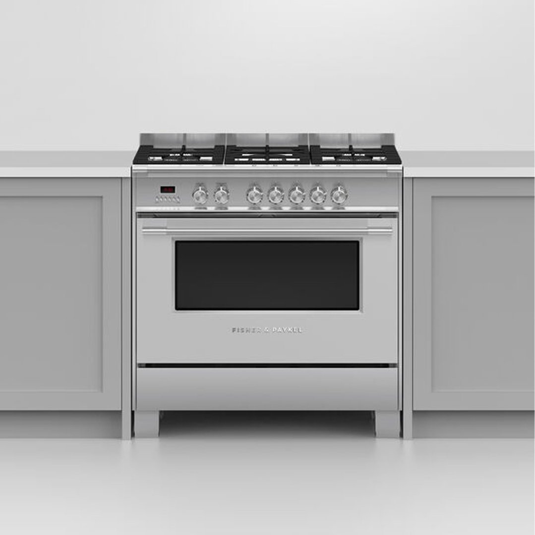 A stainless steel dual fuel cooker with five burners in a kitchen setting