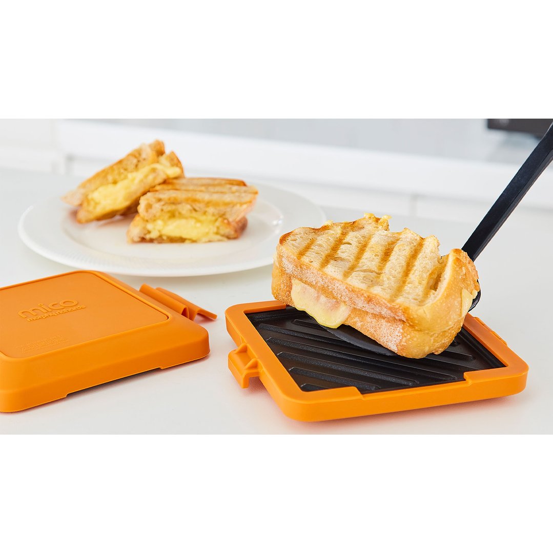 Grilled cheese sandwich being removed from an orange sandwich maker