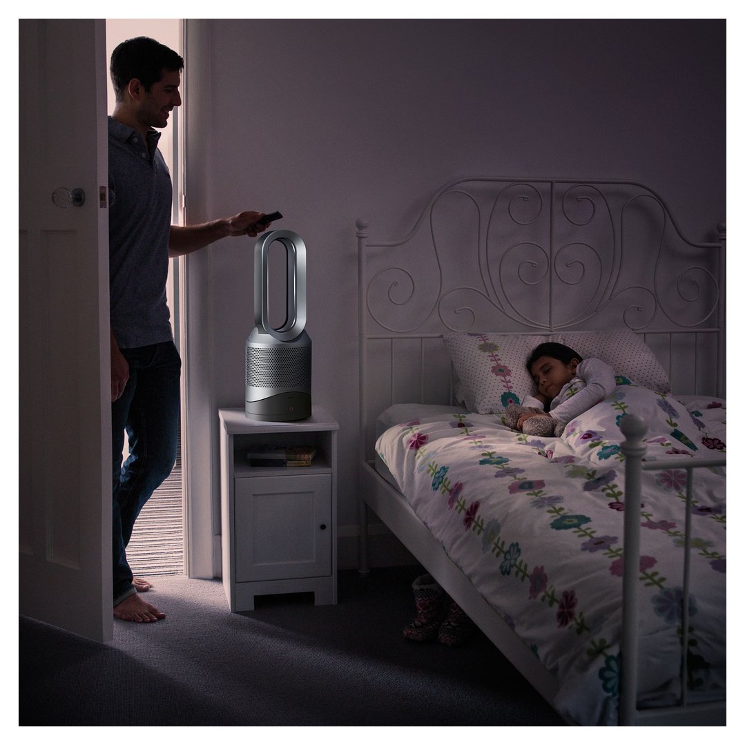 Man adjusting air purifier in child's bedroom while she sleeps