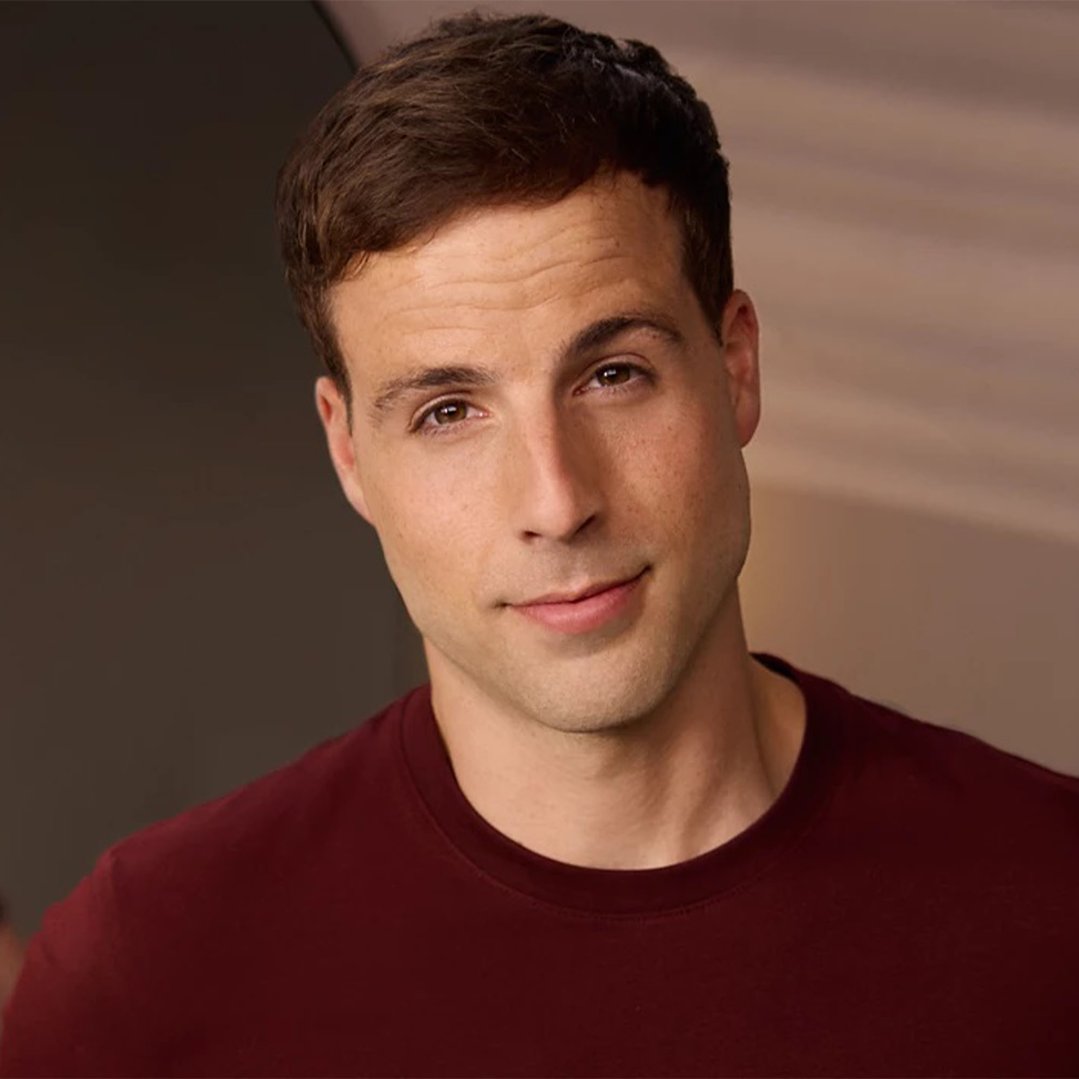 Man with short brown hair and a maroon shirt looking at the camera