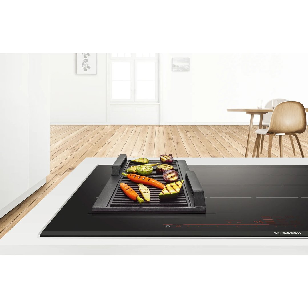 Griddle plate with grilled vegetables on a cooktop in a modern kitchen