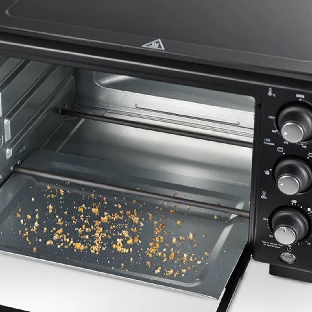 Inside view of an air fryer oven with crumbs on the bottom tray
