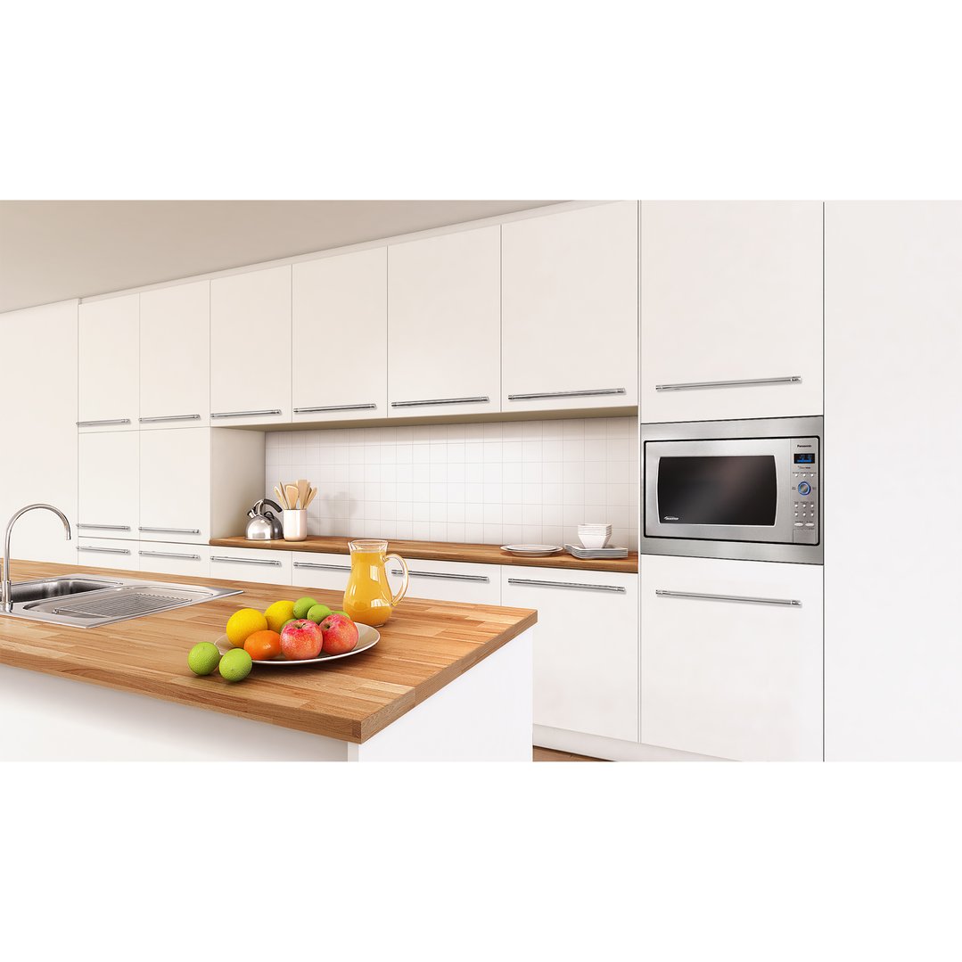 Stainless steel microwave trim kit built into white kitchen cabinetry with wooden countertop