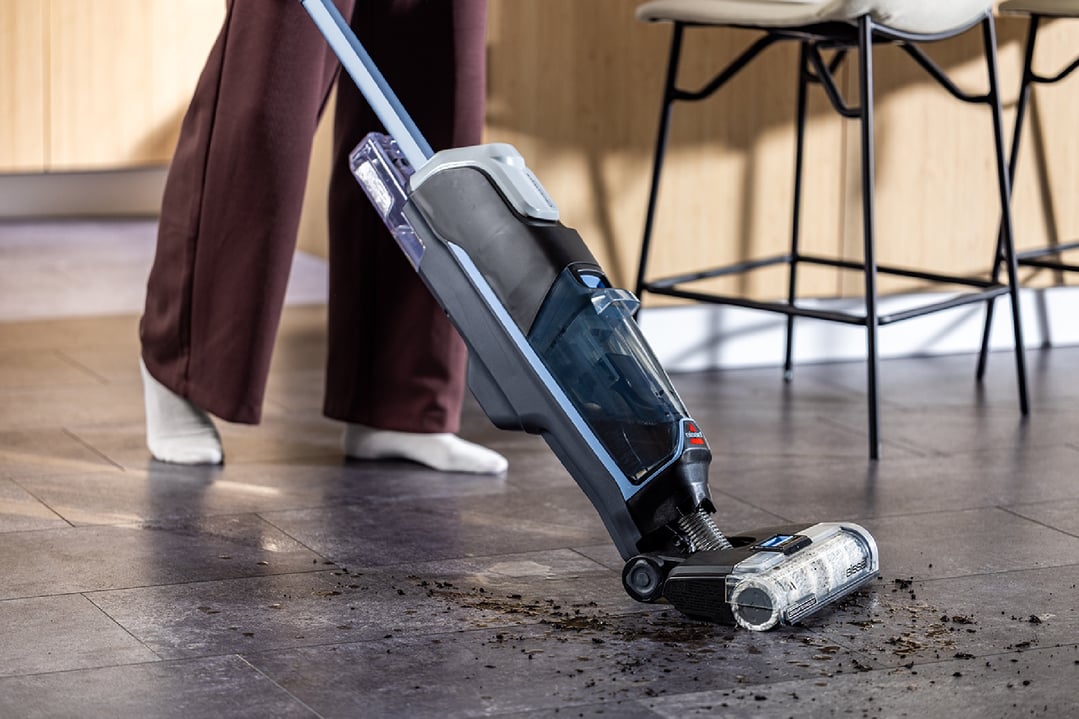 Person cleaning a dirty floor with a BISSELL CrossWave Edge Cordless handStickVacuum