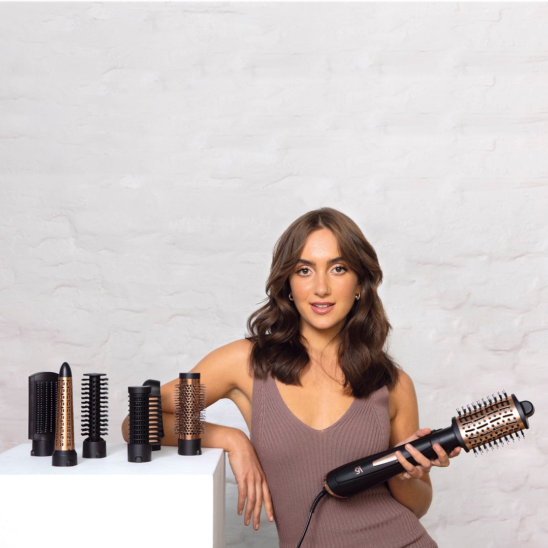 Woman holding a VS SASSOON Air Style Brilliance 7-in-1 hair styler with attachments