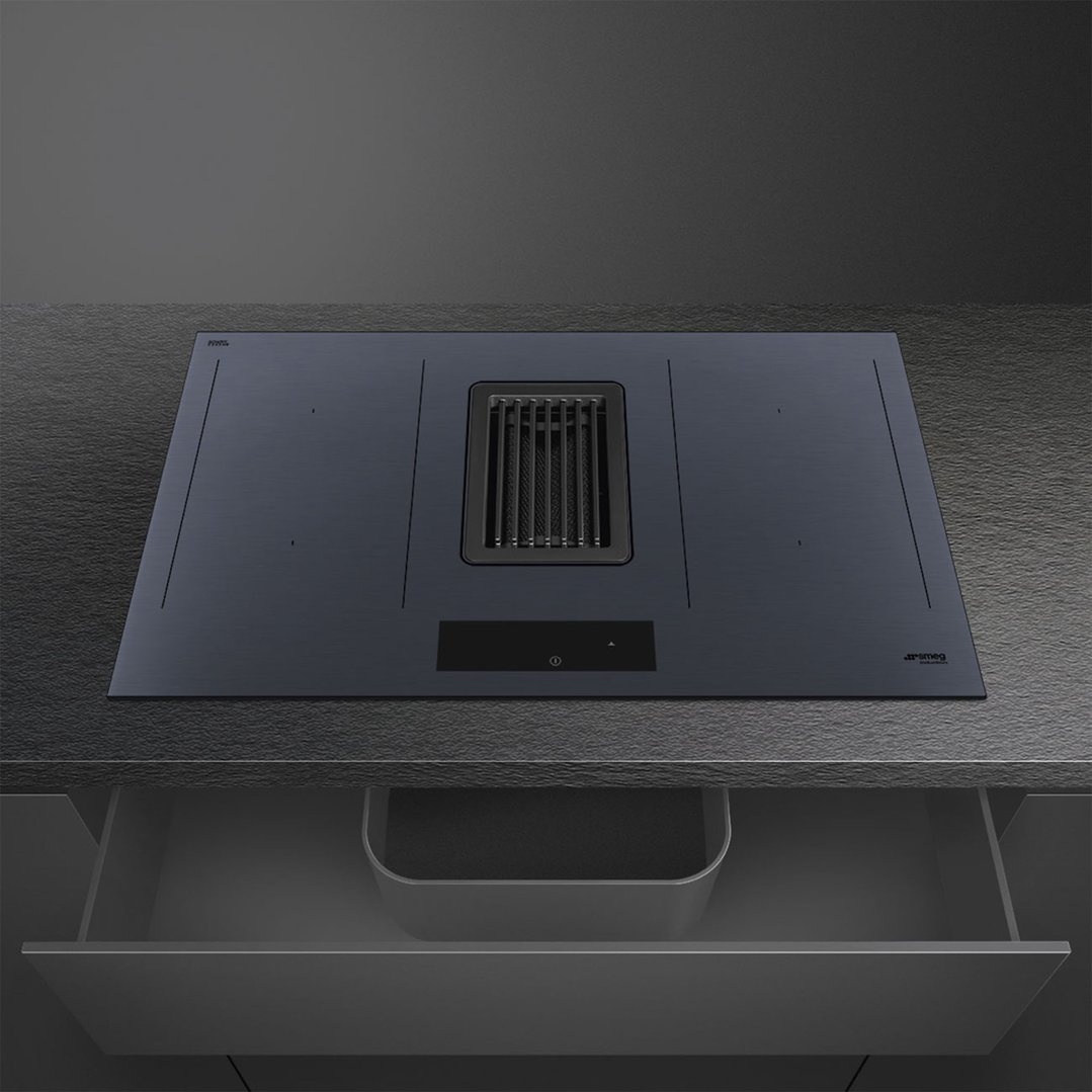 Integrated induction cooktop with downdraft extractor fan in a dark kitchen setting