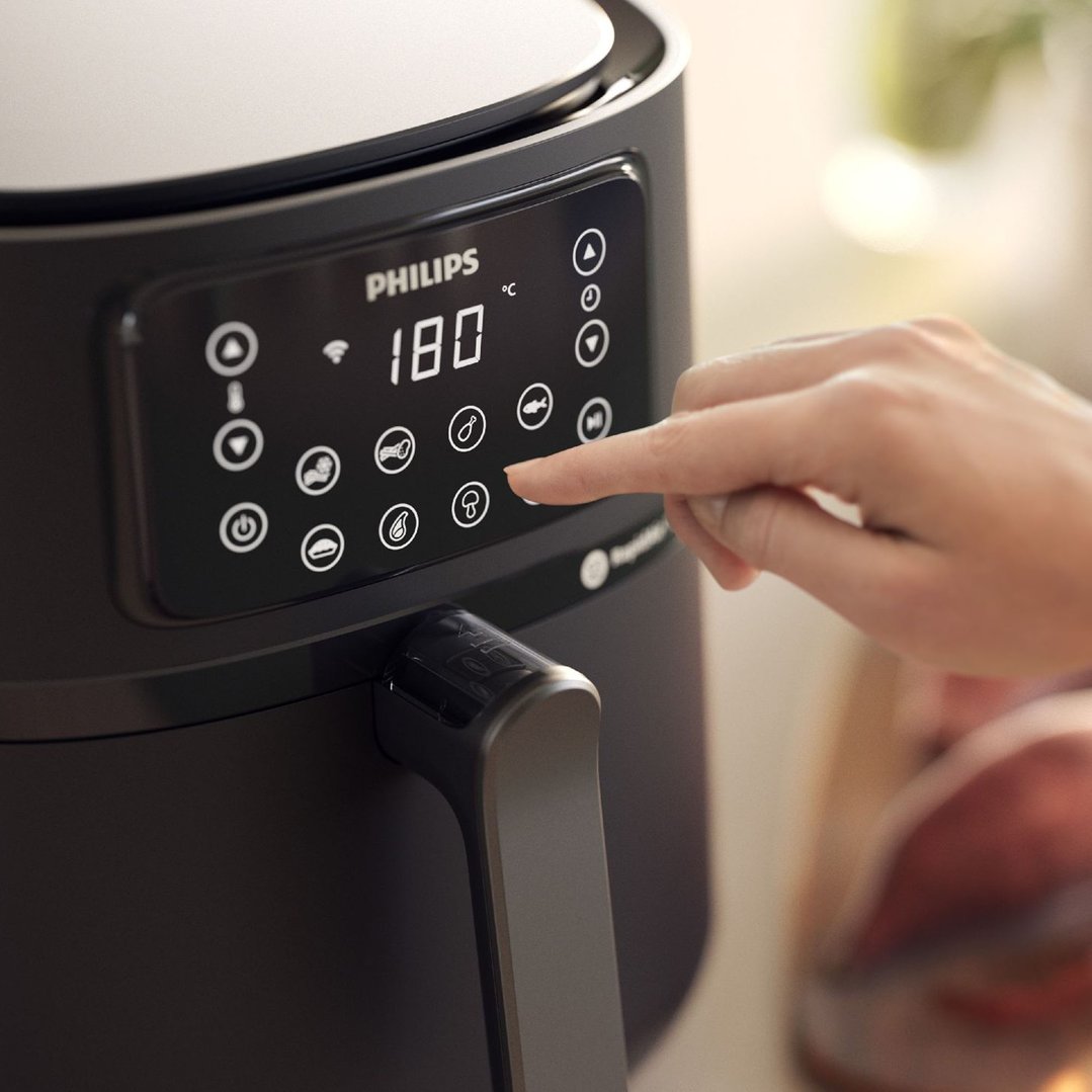 Hand touching the digital display of a Philips airfryer