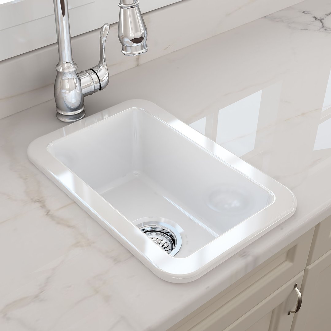 White fireclay sink with chrome faucet in a kitchen setting