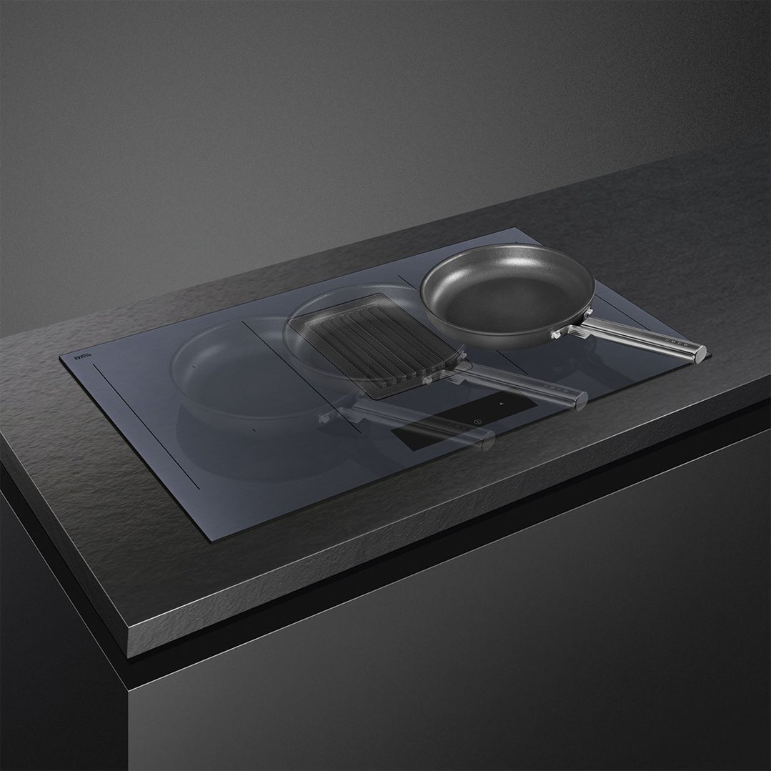 Induction cooktop with two pans on a dark countertop in a modern kitchen