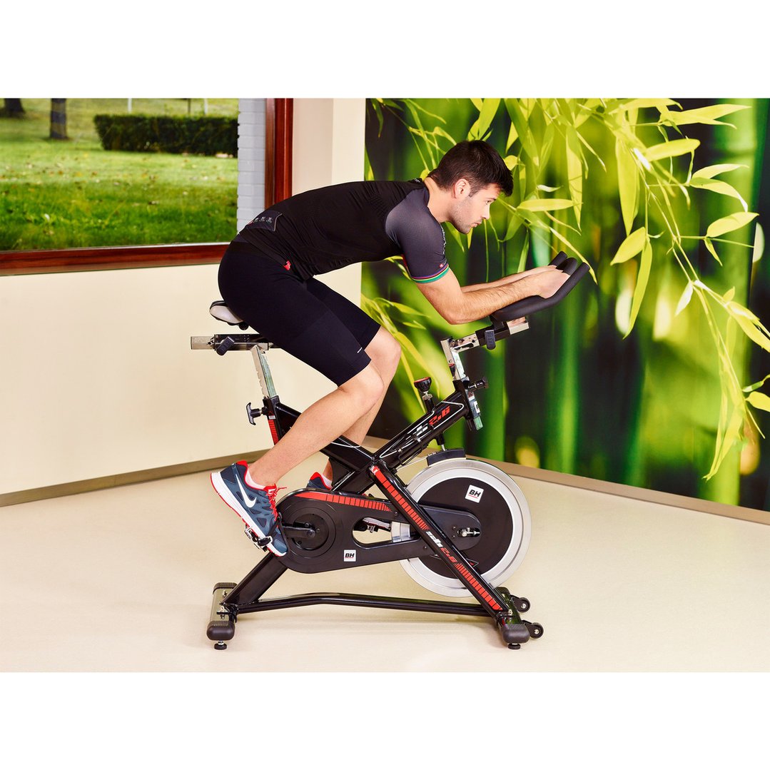Man exercising on a spin bike in a room with a window view