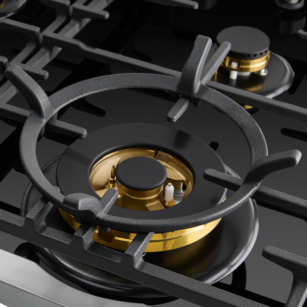Close up of a black gas on glass cooktop with cast iron trivets