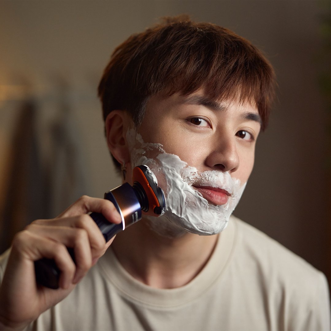 Man shaving with a Philips electric shaver and shaving cream