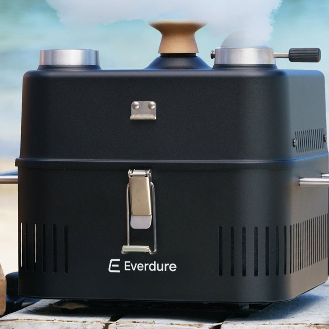 Black Everdure portable charcoal BBQ on a wooden surface outdoors