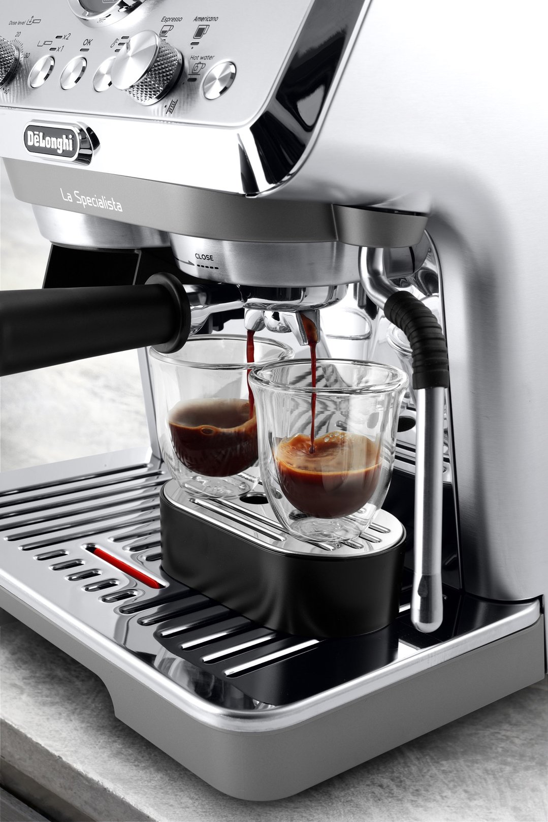 Close up of a coffee machine dispensing coffee into two glass cups