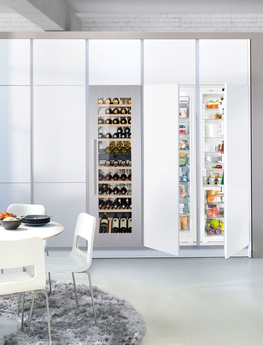 Built-in wine cabinet and two refrigerators in a modern kitchen with dining table