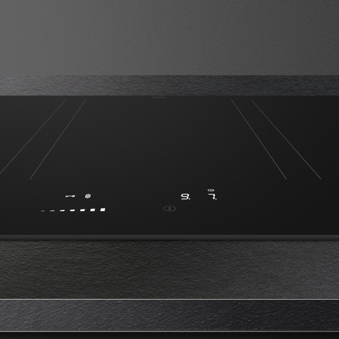 Black induction cooktop with illuminated controls in a dark kitchen setting