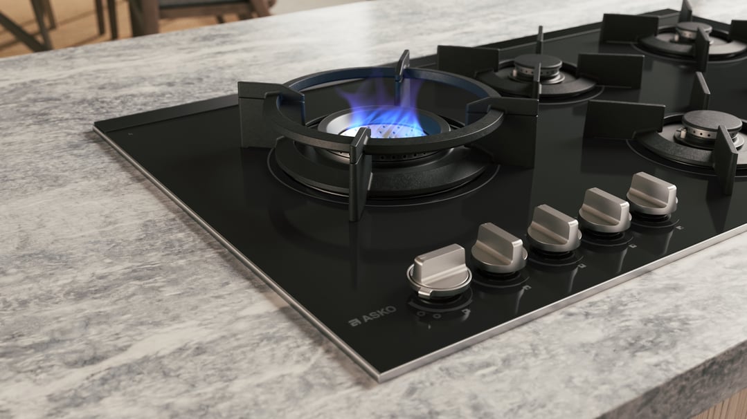 Black glass cooktop with five burners, one lit, on a grey marble countertop
