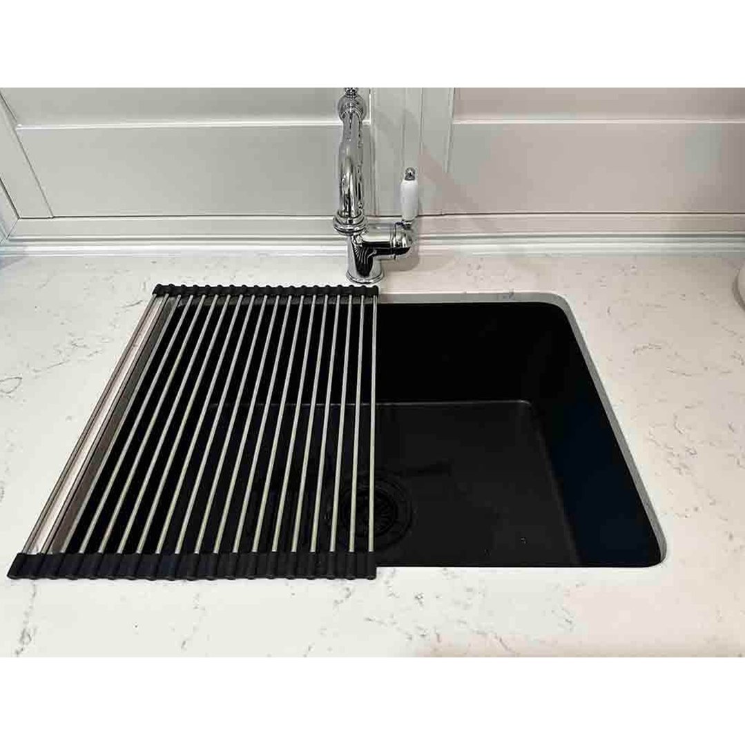 Roll-up sink drainer partially covering a black sink in a kitchen